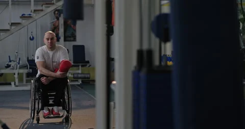A man looks sadly intently at the camera holding boxing gloves Paralympian with Video stock 154256023