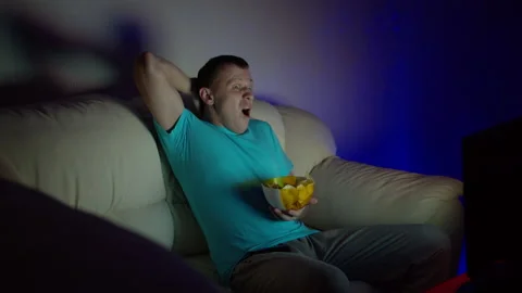 A man looks shocking the program late at night sitting watching TV Stock Footage 130961349