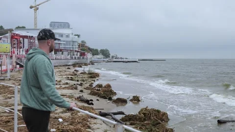 A man looks at the shore which is in the garbage Stock Footage 244721818