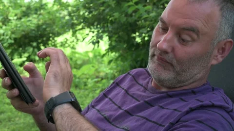 The man looks at the smartwatch while on the phone 動画素材 245152929