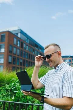 Man looks at tablet while standing outside in a city with modern buildings .. Stock Photos