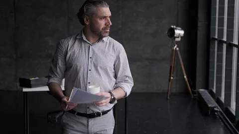 Man looks through documents and drinks coffee from a paper cup. Portrait of Stock Footage 107331397