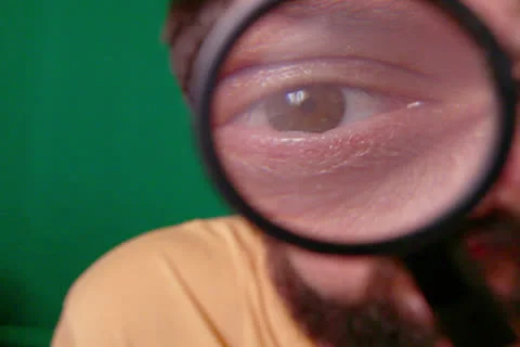 Man Looks Through Magnifier Stock-Footage 24696686