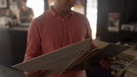Man looks through a stack of vinyl records in a record store Stock Footage 122591644