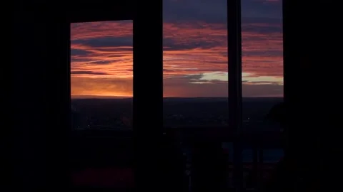Man looks at the view from the window in the evening. blue, red and orange Stock Footage 98397276