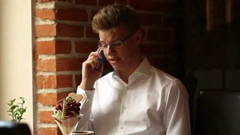 Man looks worried while speaking on cellphone in the cafe Video stock 80423510