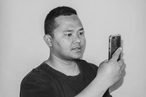 A man is lost in thought while gazing at his phone. Stock Photos