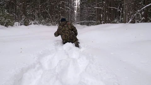 A man lost in a winter forest walks through deep, loose snow. Video stock 106245566