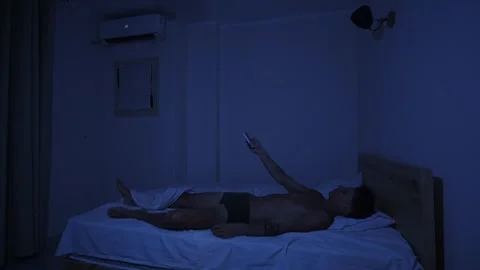 Man lowering air conditioner temperature with remote control to cool down hot Stock-Footage 346248847