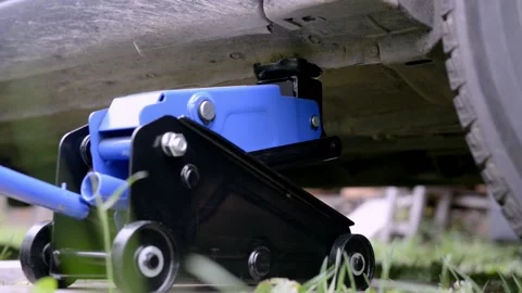 A man lowers a car using a jack after replacing a wheel or tire. Stock Footage 218814973