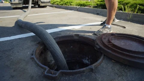 A man lowers a pipe into the sewer to pump out household waste. Stock-Footage 309298034