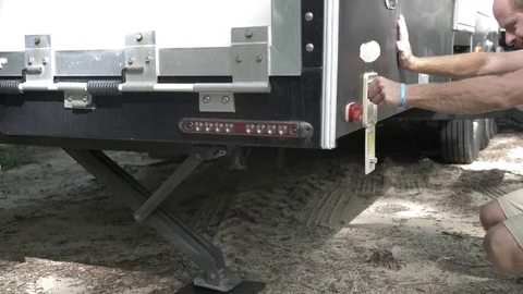 Man Lowers Stabilizers on 5th Wheel Trailer Stock Footage