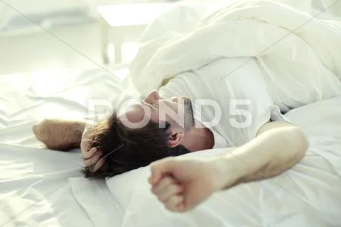Man luxuriating in bed in the morning Stock Photos