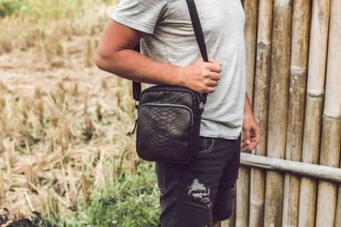 Man with luxury snakeskin python leather handbag. Bali island background. 写真素材