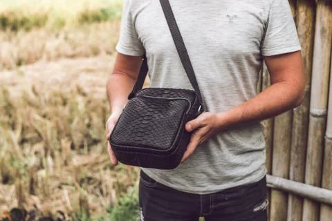 Man with luxury snakeskin python leather handbag. Bali island background. 写真素材