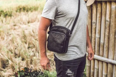 Man with luxury snakeskin python leather handbag. Bali island background. 스톡 사진