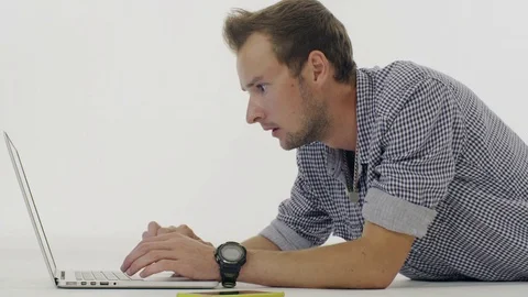 Man is lying and typing on a laptop on white background. 스톡 동영상 80353535