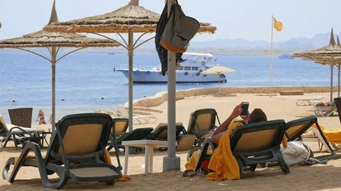 Man is lying on the beach couch under the umbrella Stock Footage 81802289