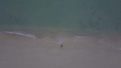 A man lying on the beach drone shoot fly up 库存影片 80564437