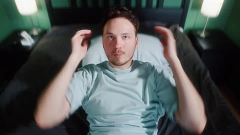 Man lying in bed and sitting up while talking 動画素材 319442536