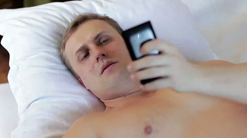 A man lying in bed and using a smartphone Stock Footage 87288127