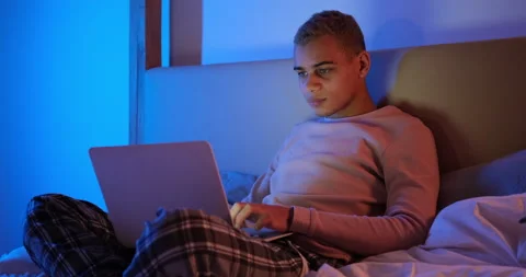 Man lying on bed and using laptop at night Stock Footage 145290172