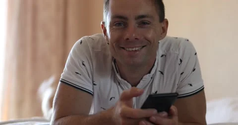 Man lying in bed and watching at the camera Stock Footage 140842983