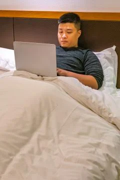 Man lying on bed and work from home on laptop Stock-Fotos