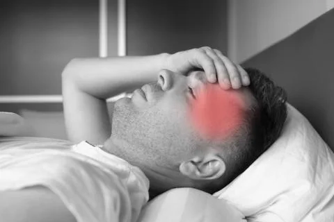 Man lying in bed at home suffering from headache or hangover Stock Photos
