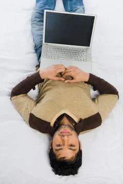Man lying on the bed with a laptop Stock Photos