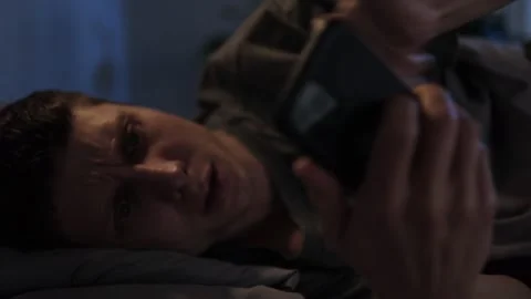 Man lying in bed late at night, glued to his phone Stock Footage 297462290