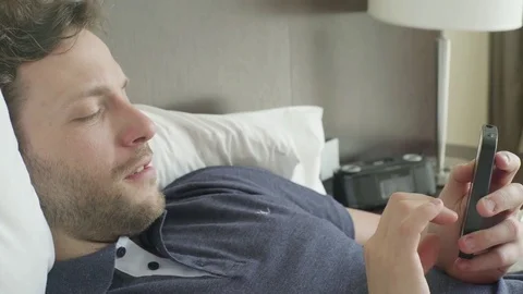 Man lying in bed looking at smart phone Stock Footage 75206494