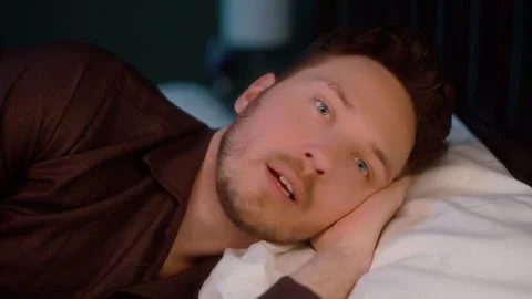 Man lying in bed at night and talking, close-up shot Video stock 319442146