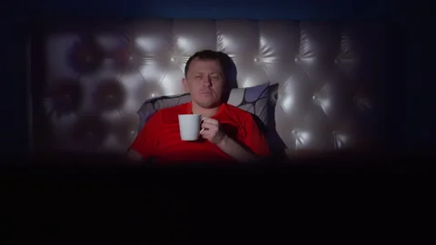Man lying in bed at night drinking tea, camera movement Stock Footage 136331745