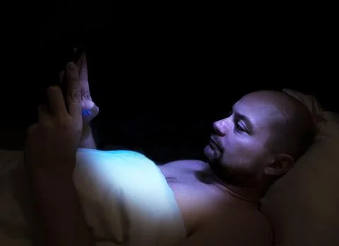 Man lying in bed at night looking at his tablet. 스톡 사진