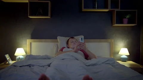 Man, lying in bed at night, using his cell phone, browsing the app, bedroom Stock Footage 204998299