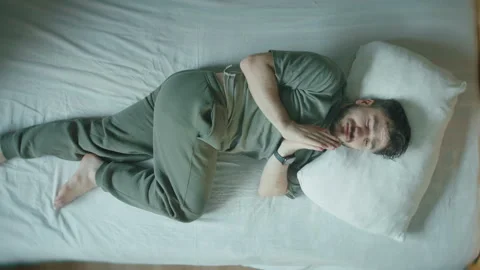 Man lying in bed praying with folded hands before falling asleep, top view Stock Footage 344102622
