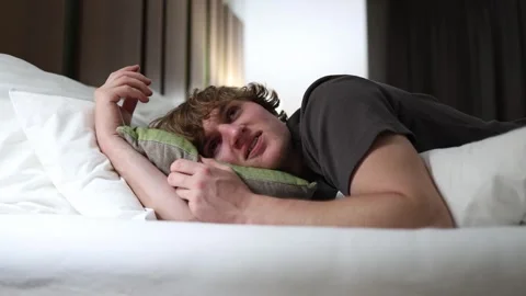 Man lying on bed staring into distance lost in deep thoughts before sleep quiet  Stock Footage 318778798