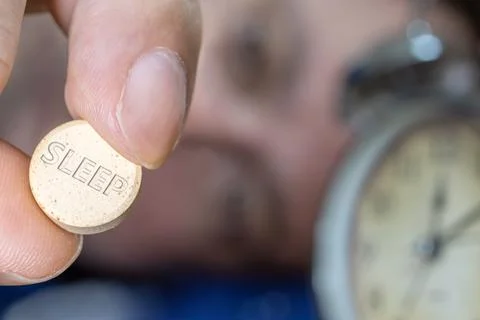 Man lying in bed taking sleeping pill after midnight, close up Stock Photos