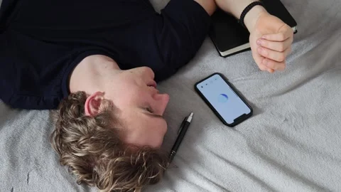 Man lying on bed talks to smartphone with open hand gesture feeling trust and ea Stock Footage 314979775
