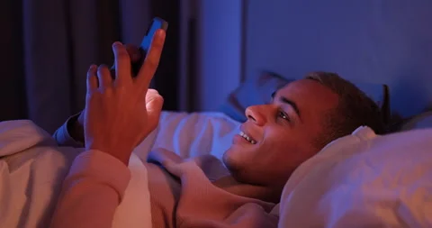 Man lying on bed text messaging on mobile phone Stock Footage 145291480