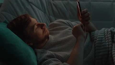 A man lying in bed uses a smartphone Stock Footage 152755003