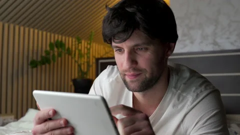 Man lying on bed using digital tablet Stock Footage 148463062