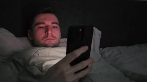 Man lying in bed using a smartphone in a dark room. Nighttime scene Stock Footage 284042377