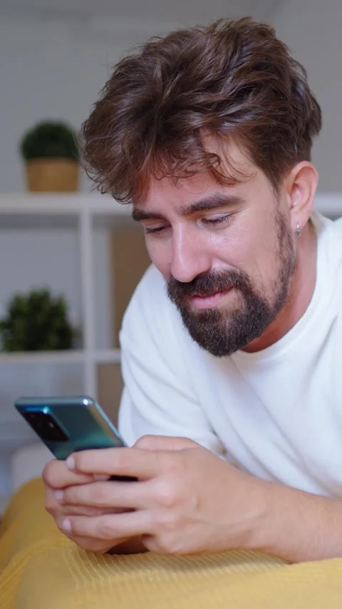 Man lying on bed using smartphone Stock Footage 315876043