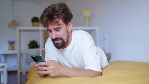 Man lying on bed using smartphone Stock Footage 316923460