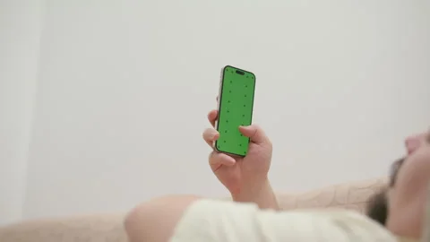 Man lying in bed using smartphone with green screen Stock Footage 340925680