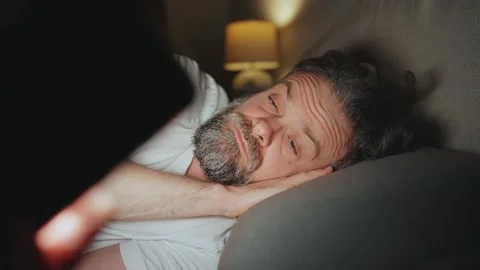 A man lying in bed using smartphone late at night. Video stock 342957963