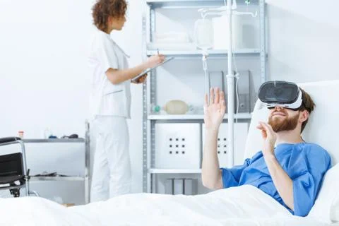 Man lying in bed in VR goggles Stock Photos