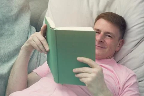 Man lying on couch and reading a book Stock Photos